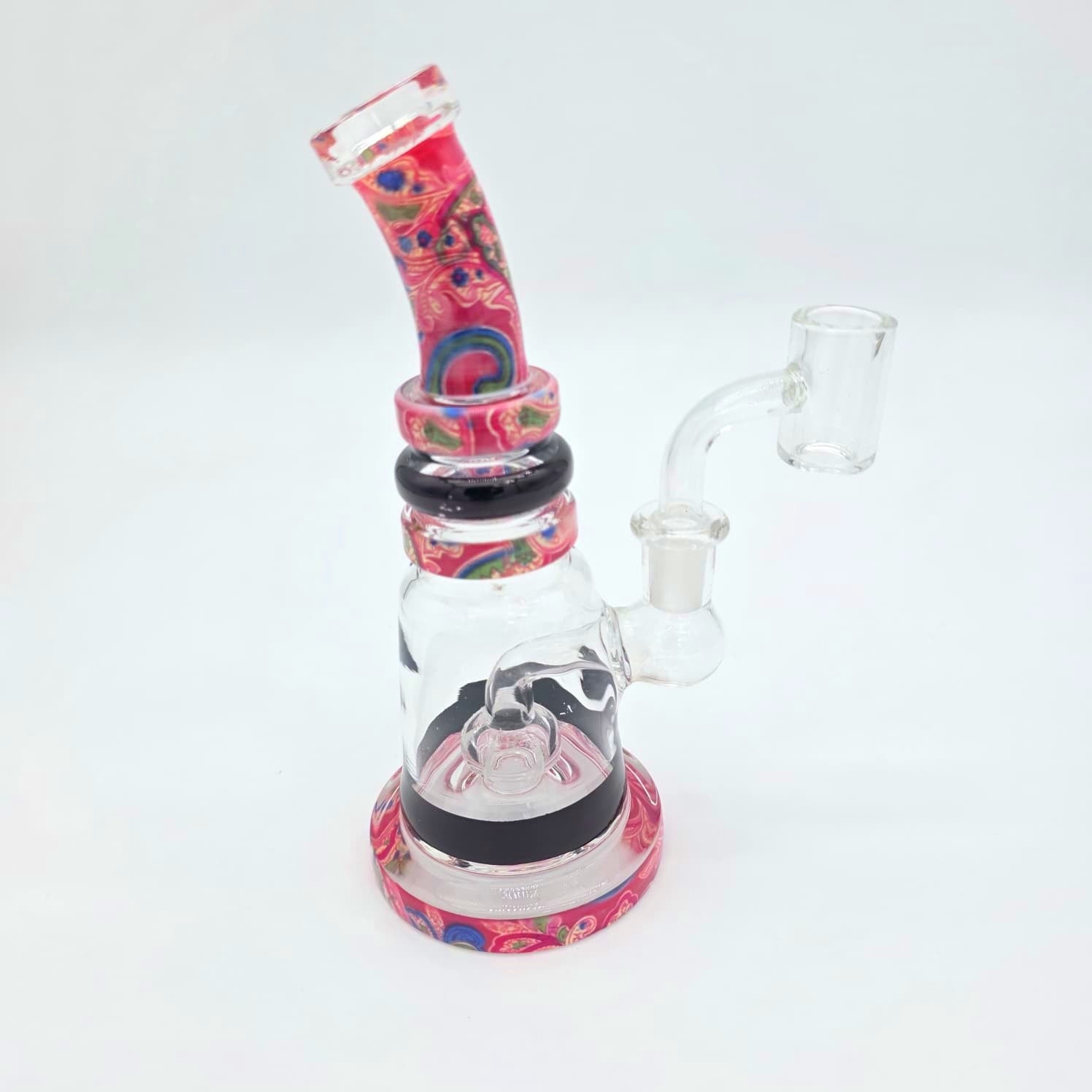 A glass water pipe with a colorful pink, red, and blue patterned base, neck, and bowl, paired with a clear glass body and side arm, set against a plain white background.